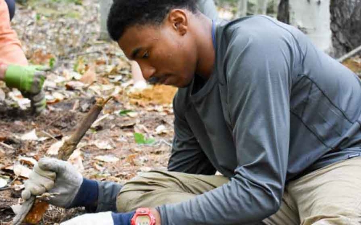 a person does work on a trail as part of a service project with outward bound